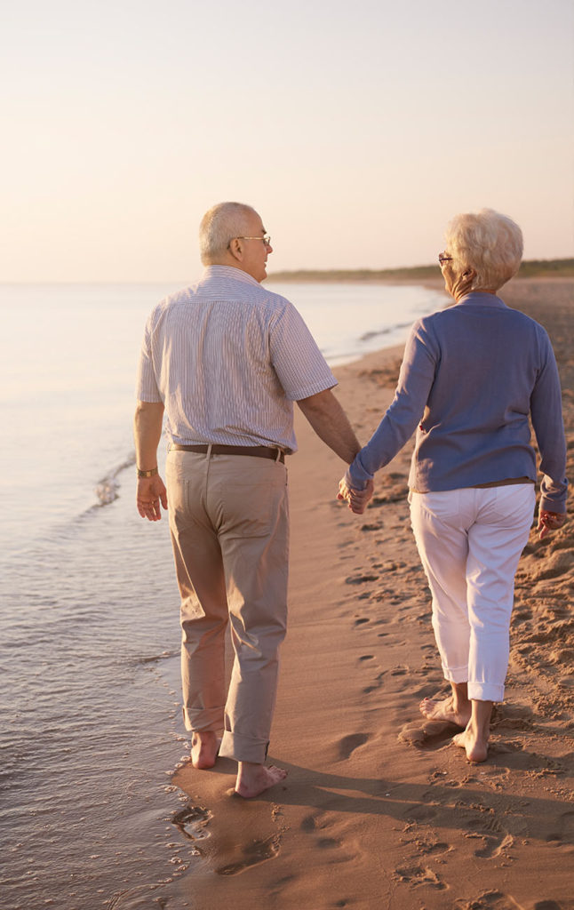 senior couple holding hands while they walk the beach safe retirement strategies colts neck nj